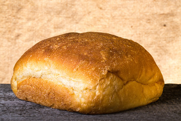 Loaf of white wheat bread on old wooden table