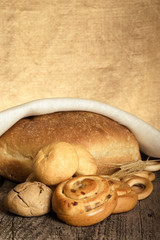 Bread assortment and wheat ears on an old wooden table. Toned