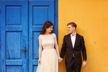 Bride and groom against yellow wall