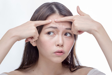 Asian woman squeezing spot on forehead