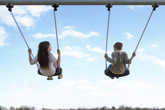 Coppia di bambini di spalle su altalena