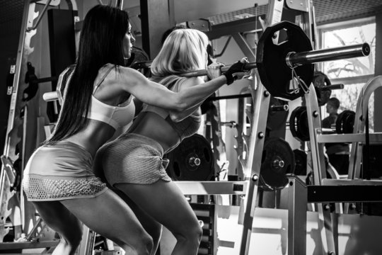Two beautiful girls working out in gym