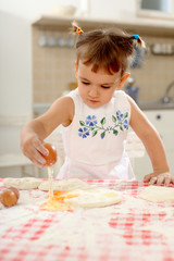 little girl playing with dough on the kitchen table