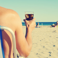 young man hanging out on the beach with a cola drink, filtered