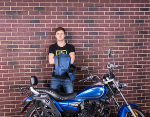 Obraz na płótnie Canvas Young Man Holding his Jacket Behind his Motorcycle