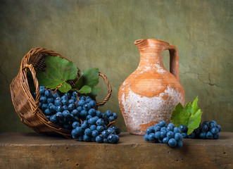 Still life with grapes on a basket and jug