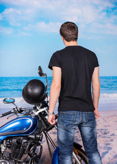 Young Man Standing next to Motorcycle on Beach