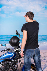 Man with Motorcycle Looking into Distance on Beach