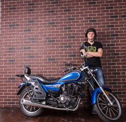 Fototapeta na wymiar Young Man Standing Beside Motorcycle Against Wall
