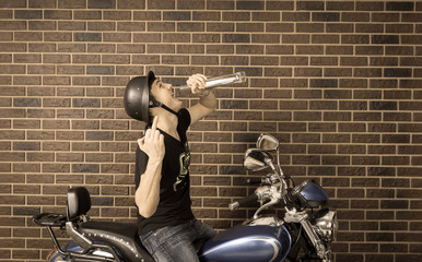 Hyped up motorcyclist sitting drinking alcohol