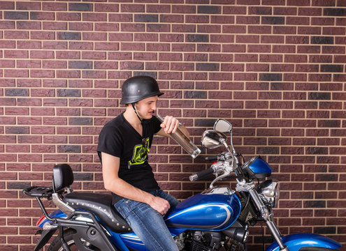 Young man sitting drinking alcohol on his bike