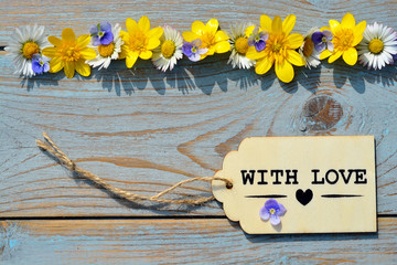 Wooden background with flowers and with love label