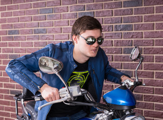 Fototapeta na wymiar Trendy young man in shades riding a motorbike