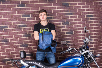 Fototapeta na wymiar Young Man Standing with his Jacket and Motorcycle