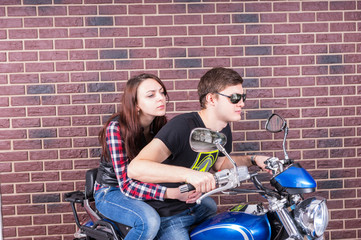 Fototapeta na wymiar Cool Couple on Motorcycle in front of Brick Wall