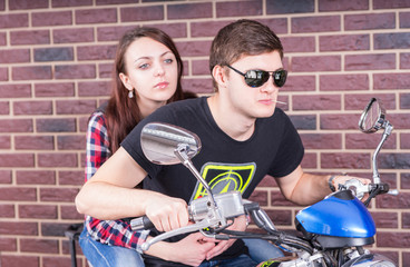 Fototapeta na wymiar Young Couple on Motorcycle in front of Brick Wall