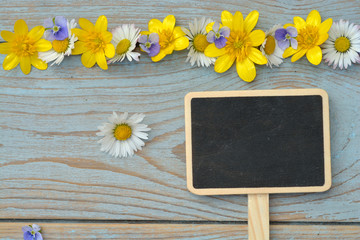 wooden background with chalk board and field flowers