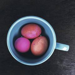 Colored easter eggs in ceramic cup on wooden background - vintag