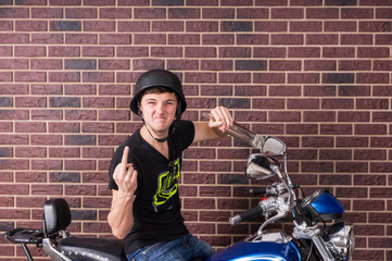 Fototapeta na wymiar Young Man on Motorcycle Giving Finger to Camera