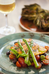 organic Arctic char fish on a bed of roasted tomatoes topped wit