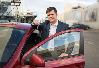 happy man posing with new car and showing keys