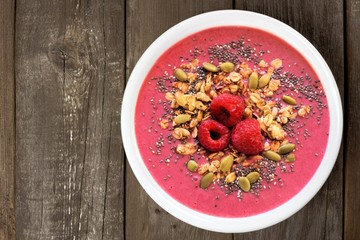 Healthy raspberry smoothie bowl on rustic wood background