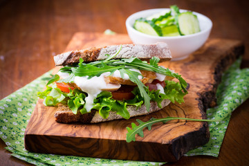 Rye toast sandwich with green leaf, tomato and chicken