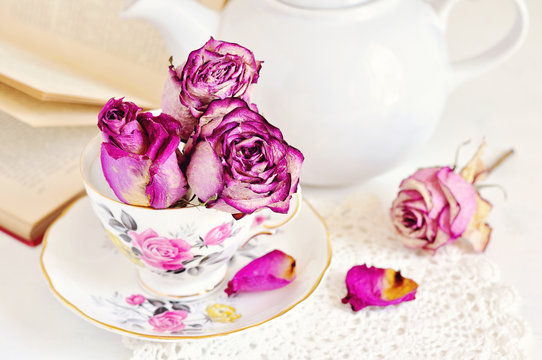Vintage tea setting with dry roses on white background