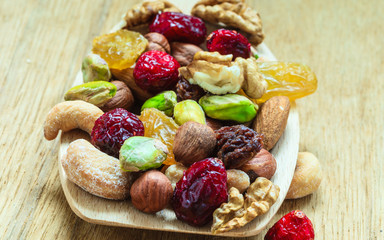 Varieties of dried fruits and nuts on wooden spoon.