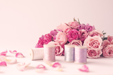 Vintage pink peonies and threads over beige background