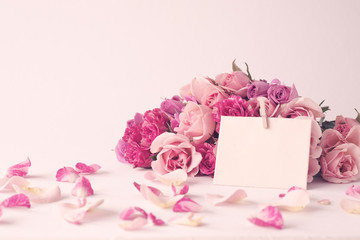 Vintage pink peonies and blank note over beige background