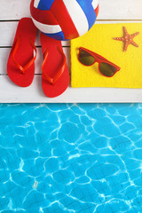 Naklejka premium Flip flop shoes and sunglasses of young people near hotel pool