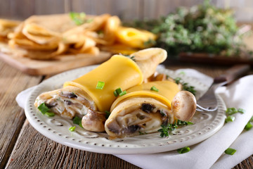 Pancakes with creamy mushrooms in plate on wooden table,