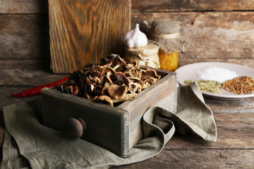 Dried mushrooms in crate on wooden background