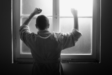 Female cancer patient leaning on the hospital window