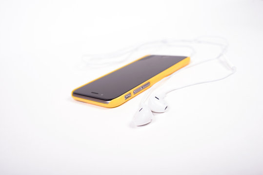 white headphones connected to black phone in yellow case