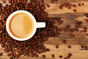 Cup of coffee with grains on rustic wooden table, top view