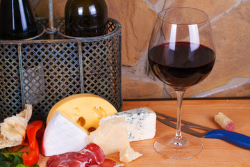 Glass and bottle of wine, cheese and prosciutto