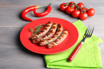 Grilled sausages on plate with vegetables on table close up