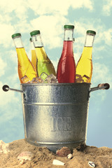 Bottles of tasty drink in metal bucket with ice