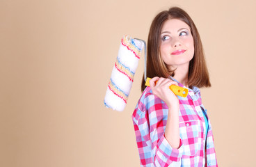 Beautiful girl with roller near wall