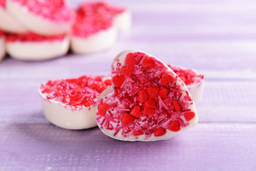 Delicious chocolate candies in heart shape on table close-up