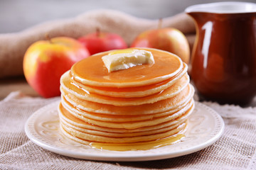 Delicious pancakes with honey on plate on table close-up