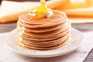 Delicious pancakes with honey on plate on table close-up