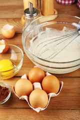 Preparation cream with eggs in glass bowl on wooden background