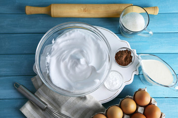 Fototapeta na wymiar Whipped egg whites for cream on wooden table, top view
