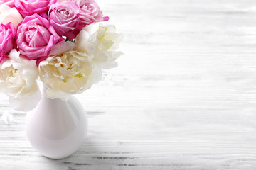 Bouquet of fresh roses and tulips on wooden background