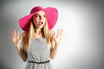 Expressive young model in pink hat on gray background