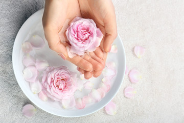 Female hands with bowl of aroma spa water on table, closeup