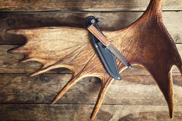 Foto auf Acrylglas Jagd Elchgeweih mit Jagdmessern auf Holzuntergrund